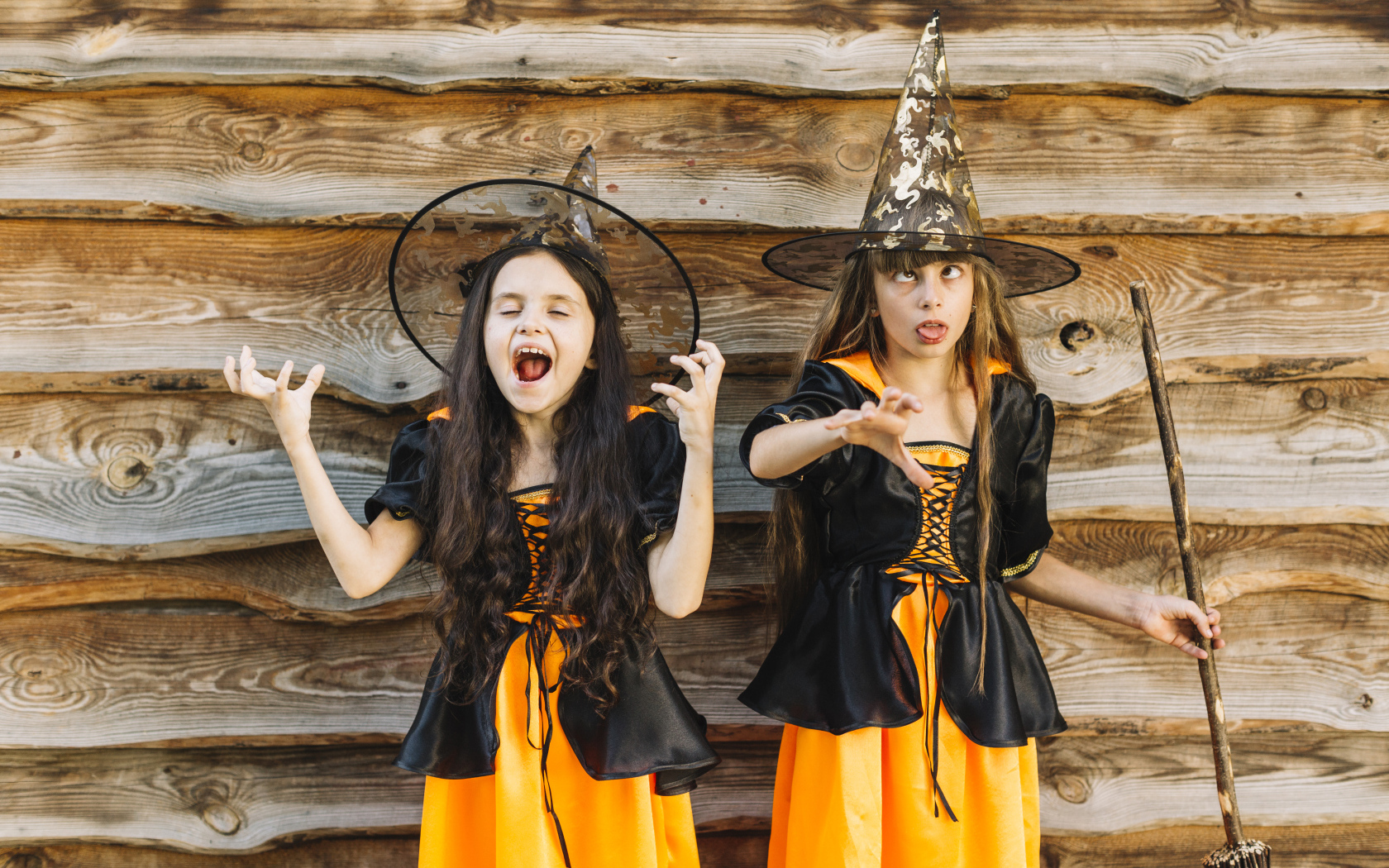 Две девочки в костюме ведьмы у стены на Хэллоуин
