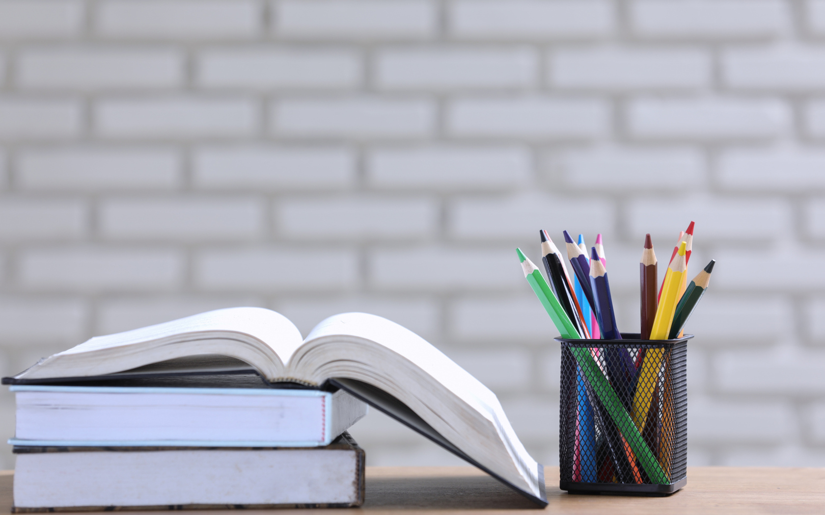 Разноцветные карандаши на столе с книгами 