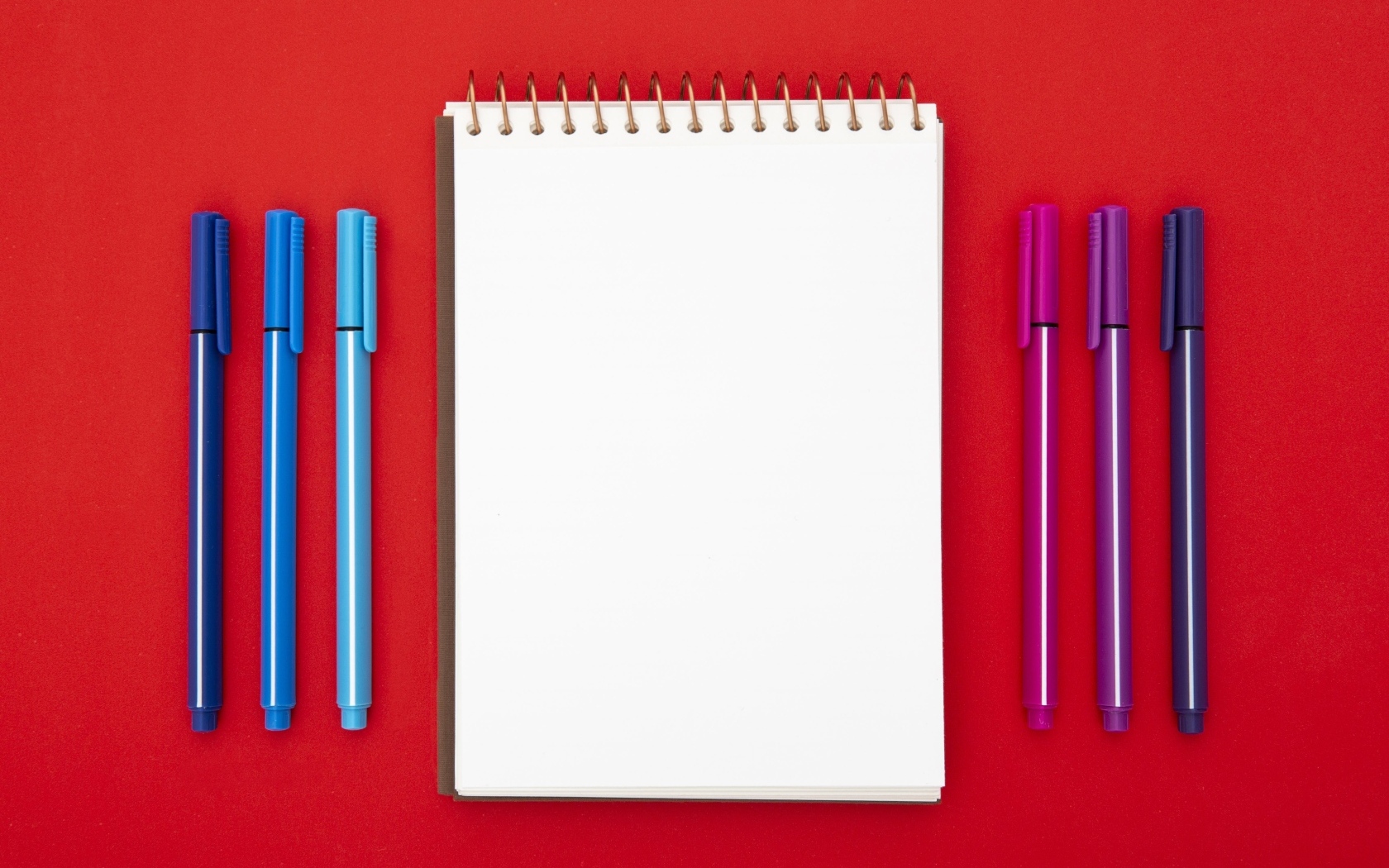 Блокнот и фломастеры на красном фоне