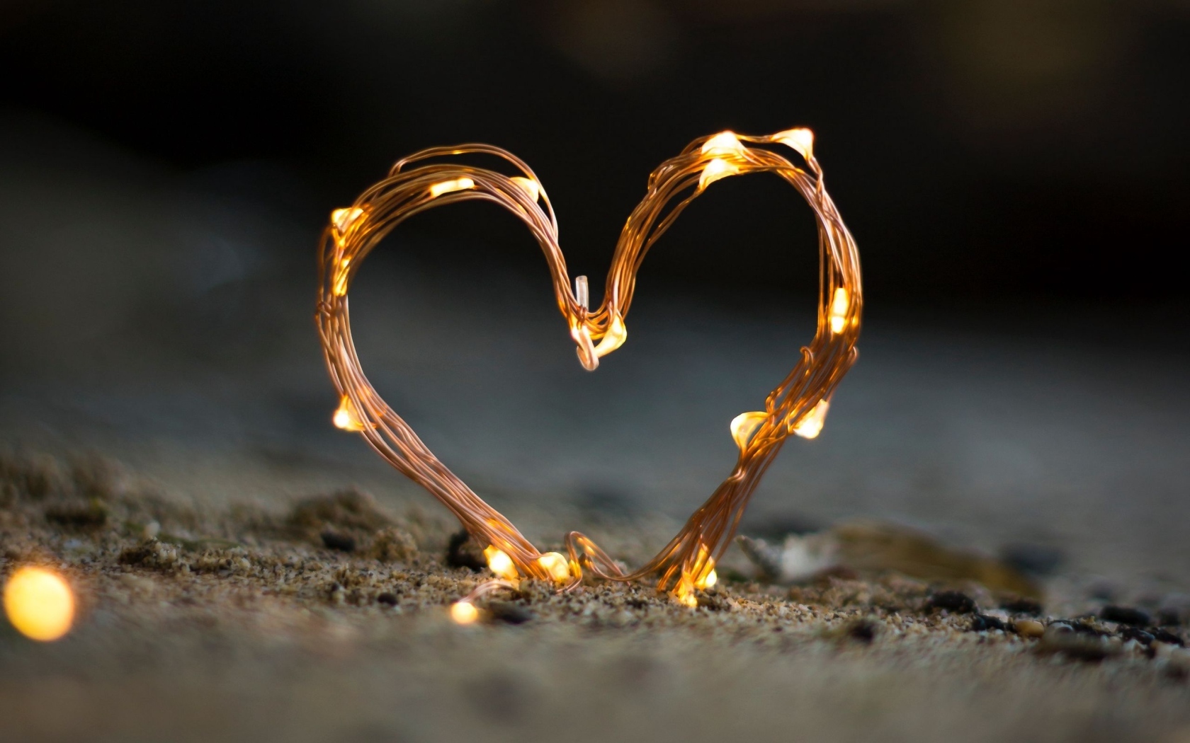 Сердце из гирлянды на песке