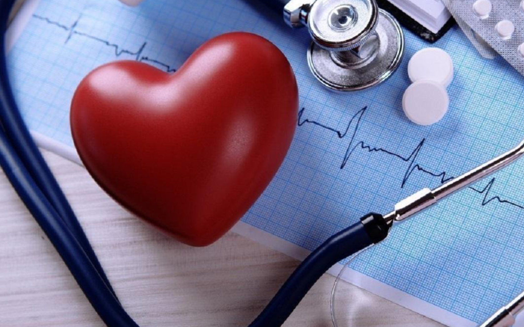 Красное сердце на столе с кардиограммой и стетоскопом