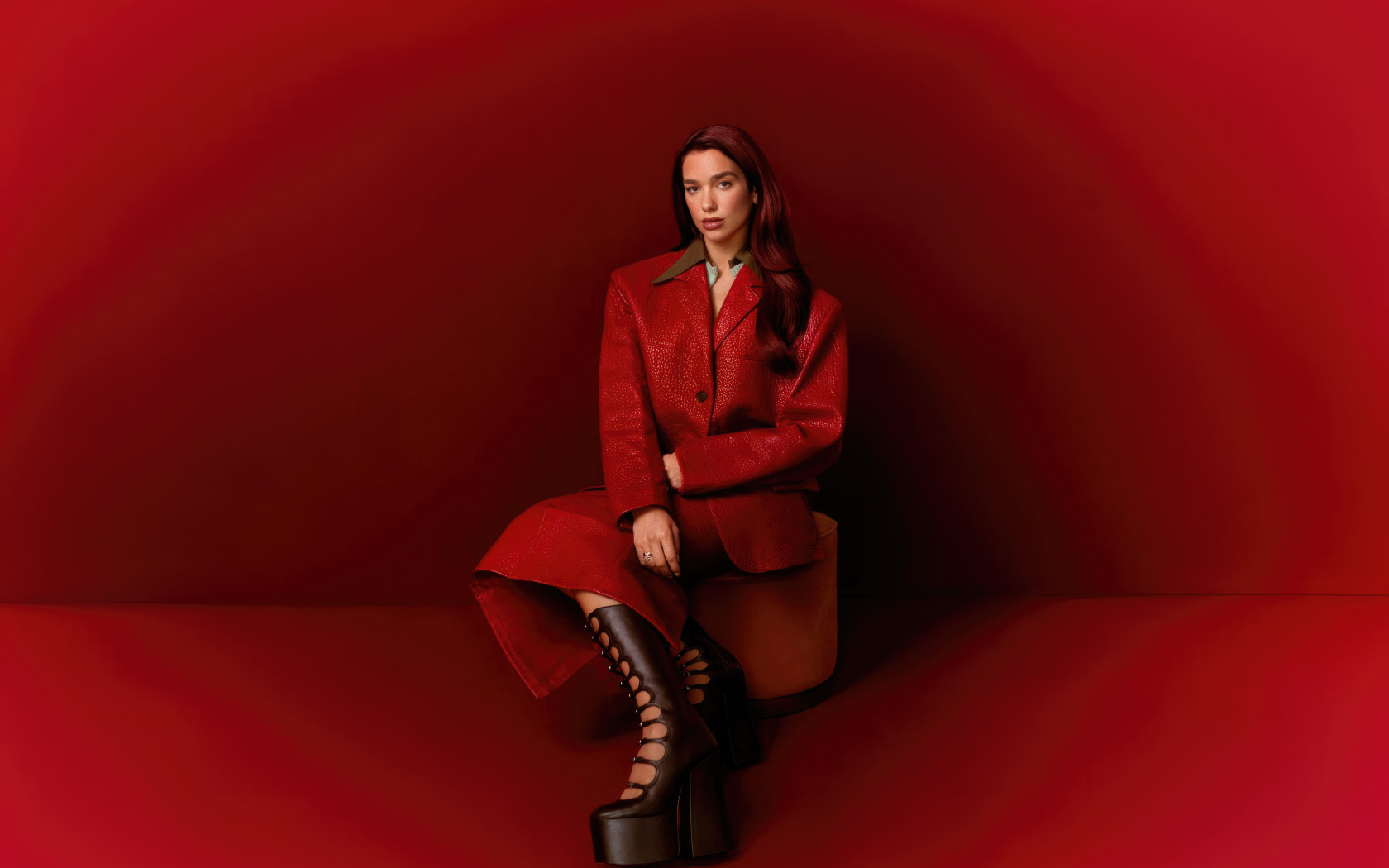 Певица Дуа Липа позирует на красном фоне
