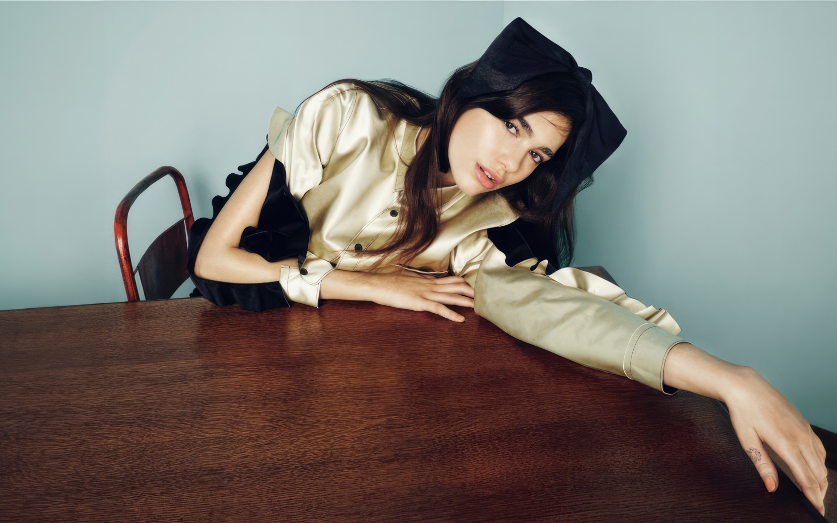 Певица Дуа Липа сидит за деревянным столом