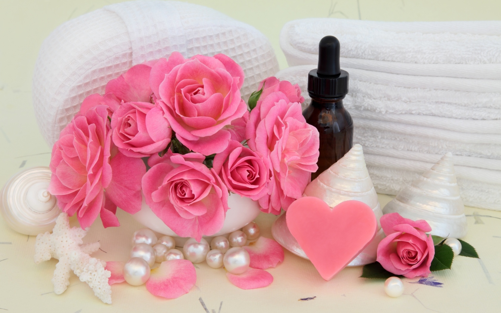 Розовые розы с полотенцами, ракушками и маслом на столе