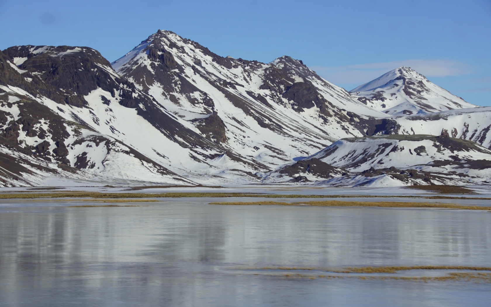 Горы в снегу под голубым небом у воды