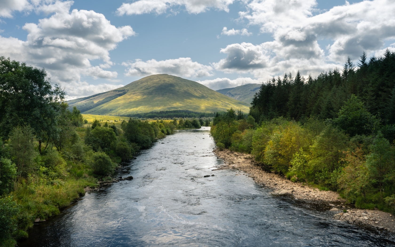 Белые облака в голубом небе над рекой в горах