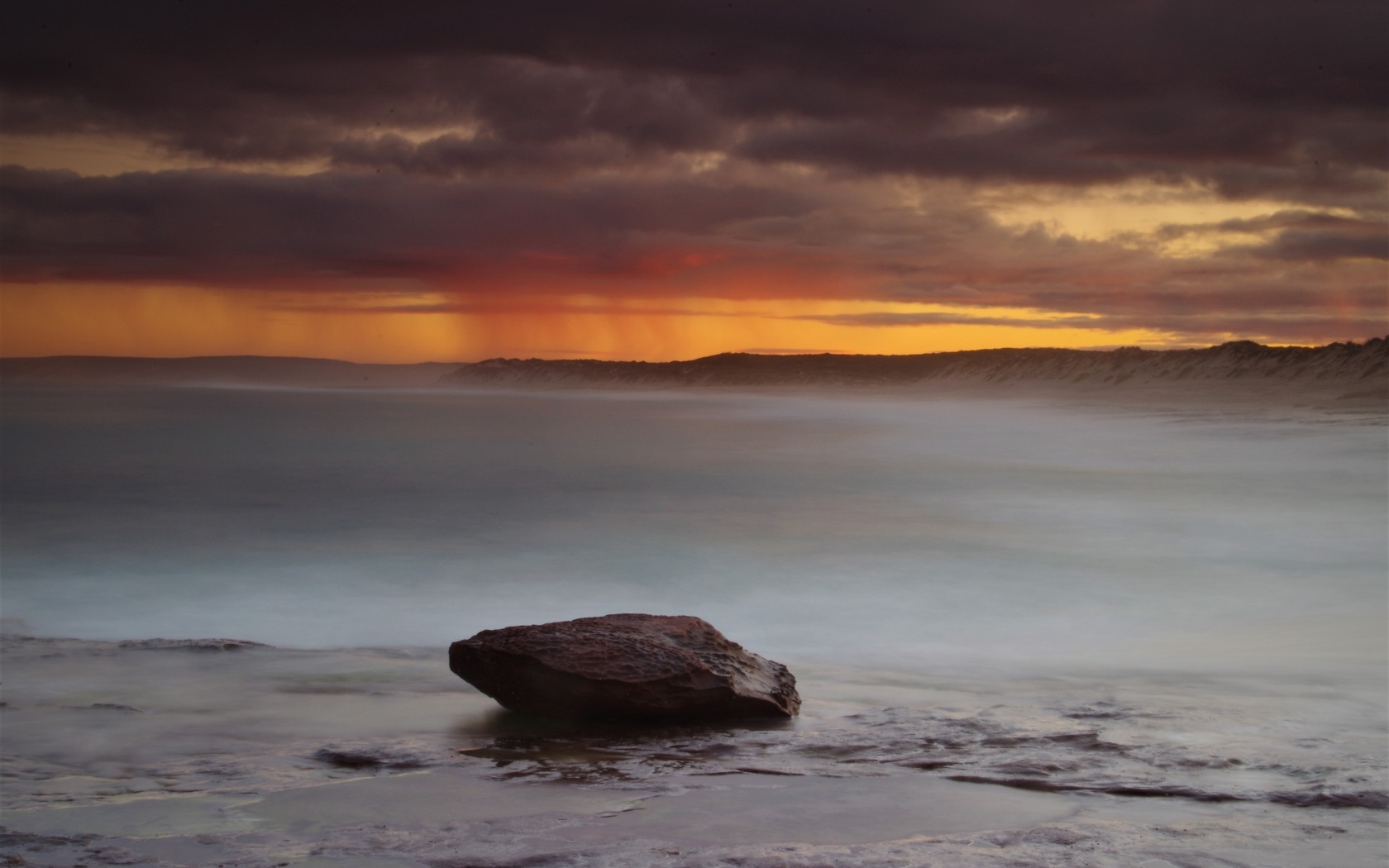 Большой камень в воде на фоне грозового неба в море