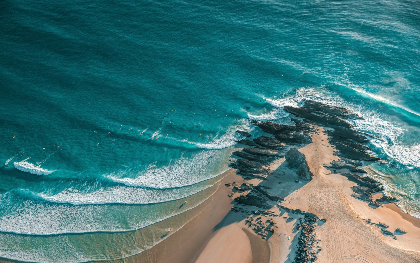 Песчаный берег с большими камнями у океана