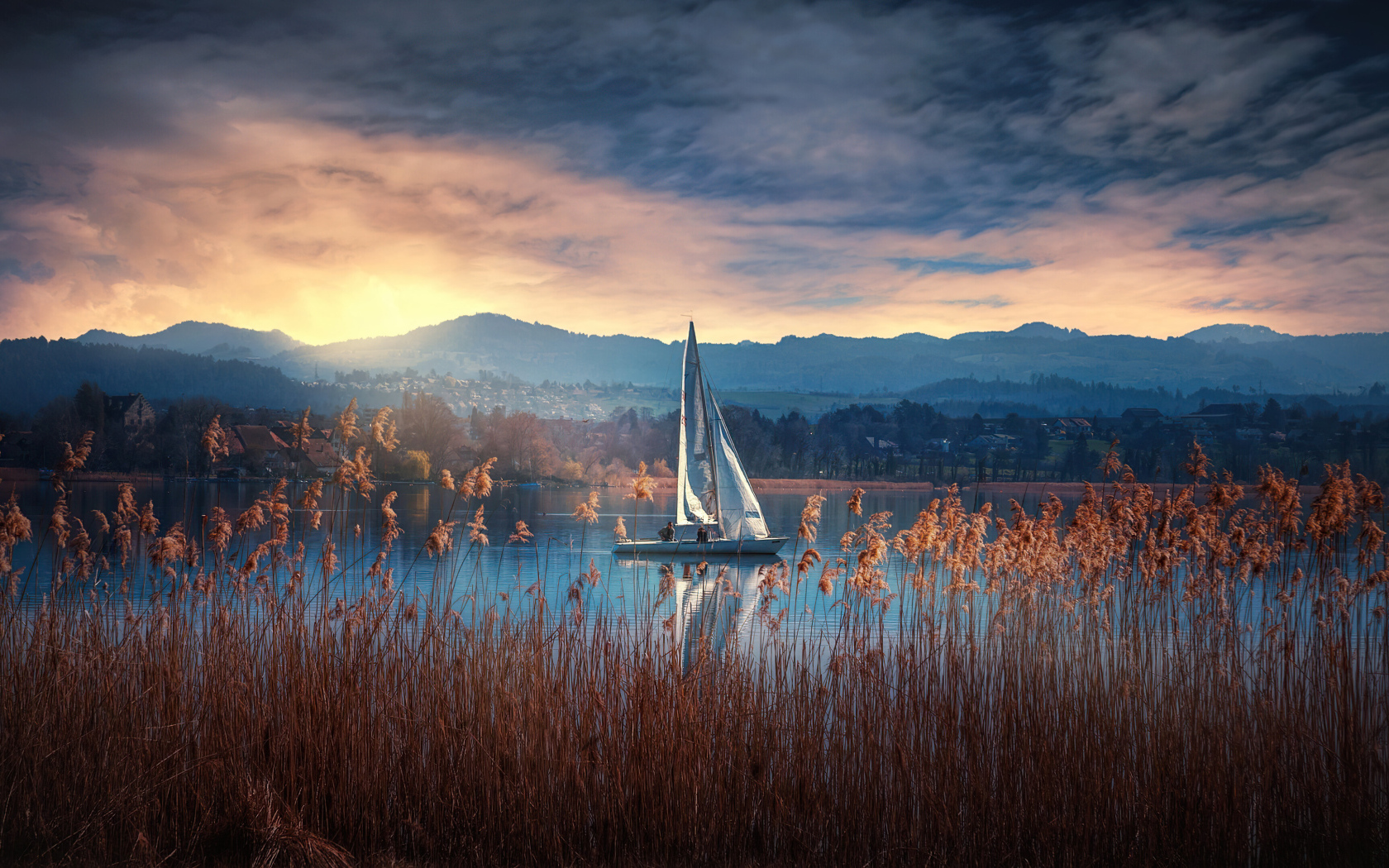 Парусная лодка на озере на закате солнца