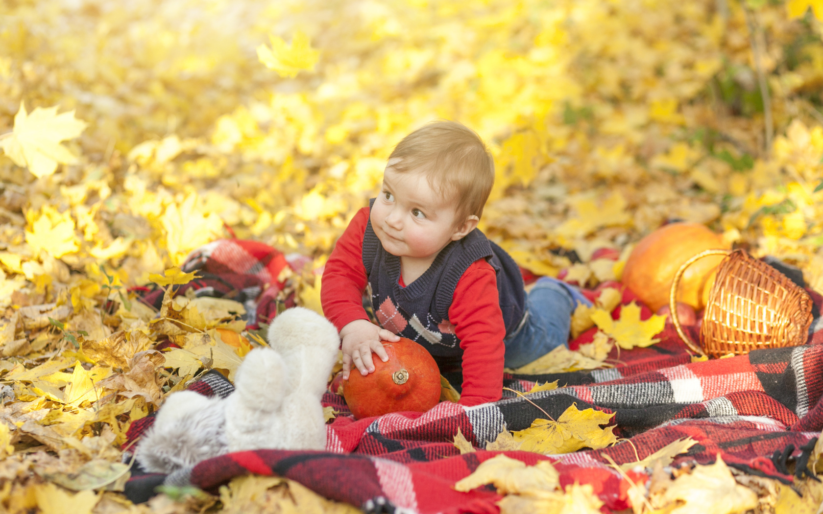 Маленький ребенок лежит на покрывале на земле осенью