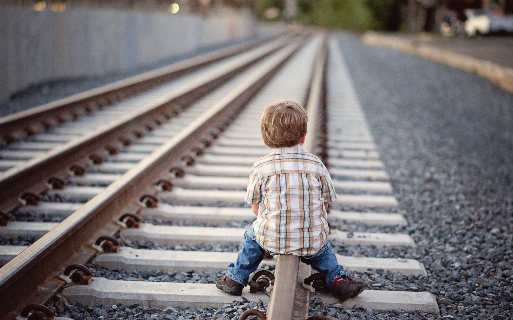 Мальчик сидит на железнодорожных рельсах