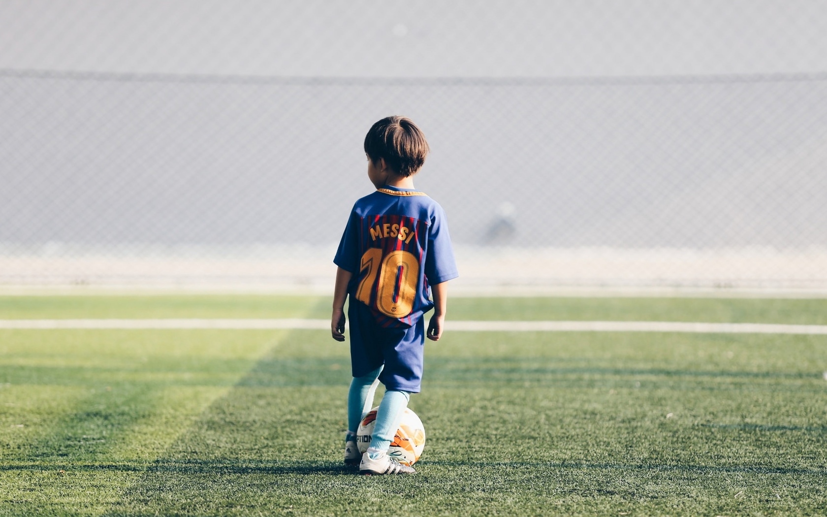 Мальчик футболист с мячом на поле