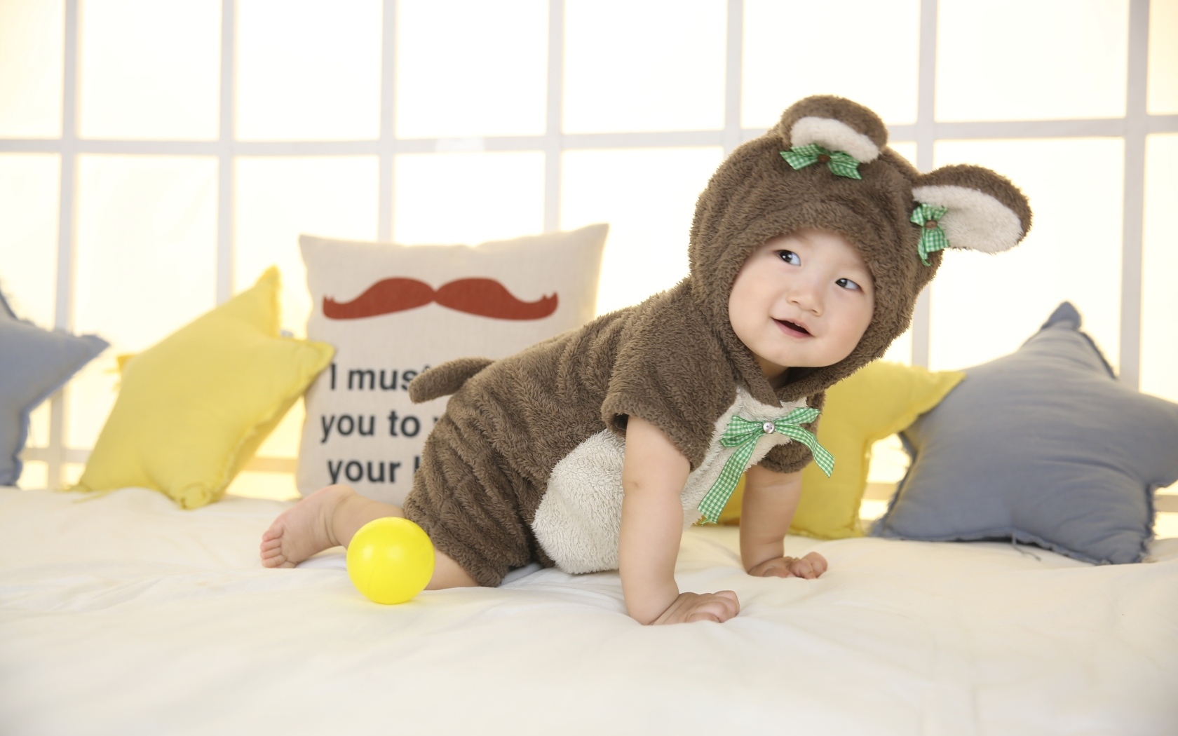 Смешной ребенок азиат в костюме на кровати