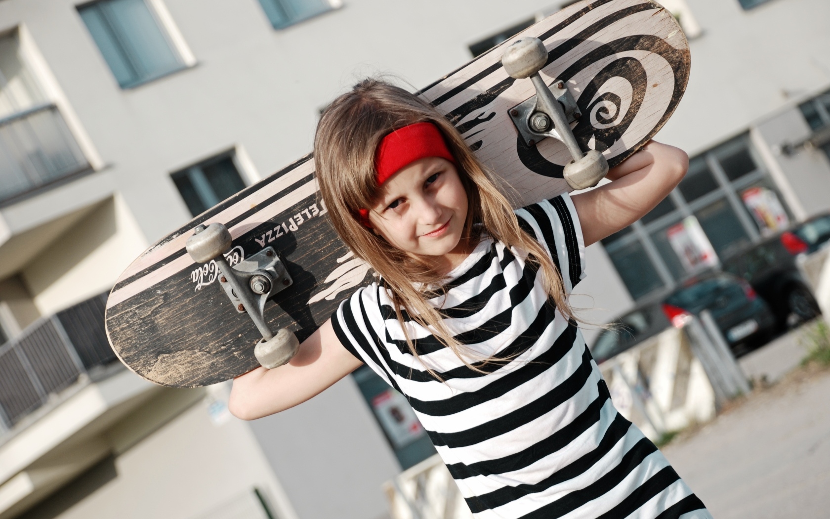 Девочка в полосатом платье со скейтбордом в руках