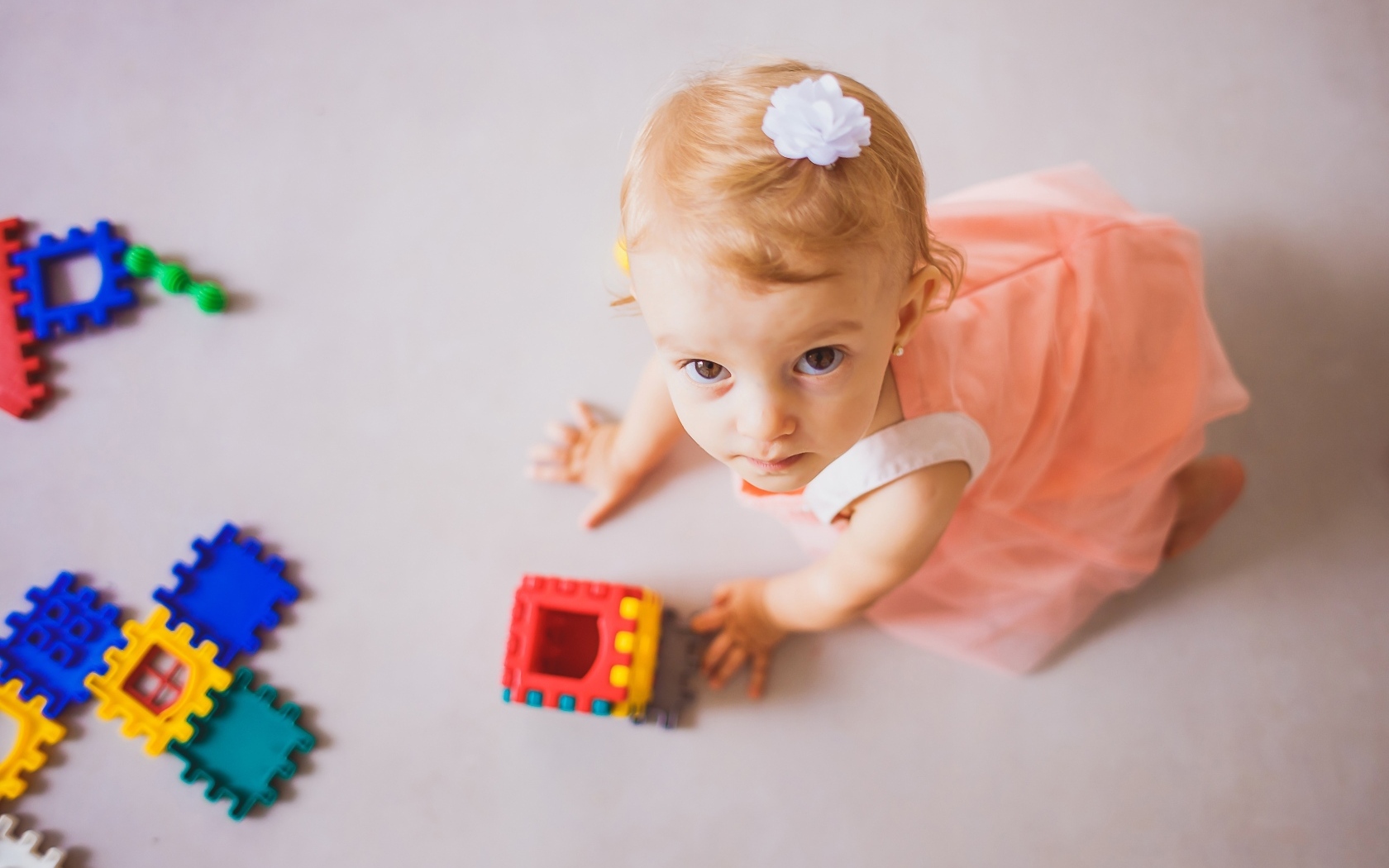 Маленькая девочка играет на полу с конструктором