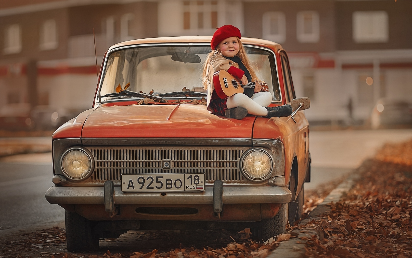Маленькая девочка с гитарой сидит на красном автомобиле осенью