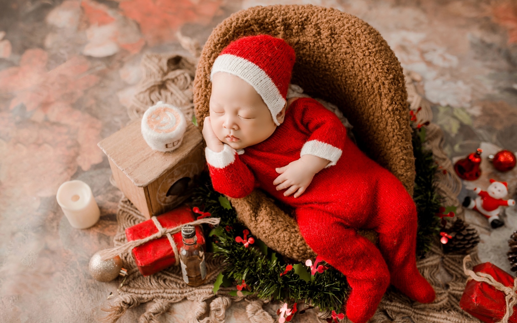 Спящий новорожденный ребенок в красном новогоднем костюме