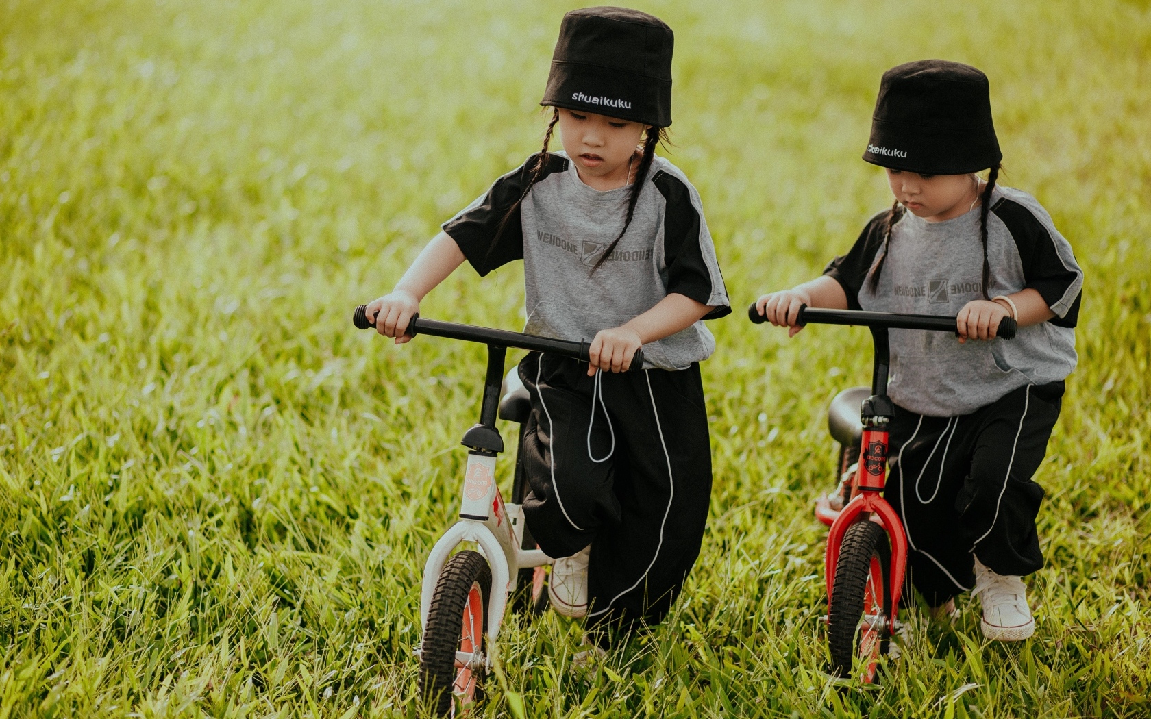 Две девочки с велосипедами на зеленой траве