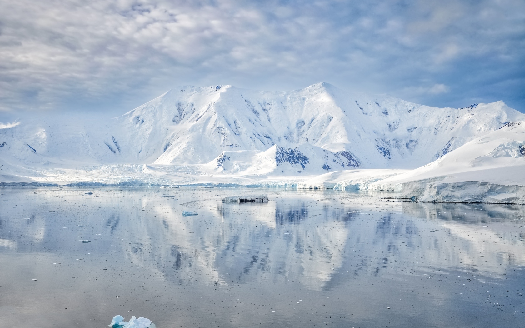 Заснеженные горы под белыми облаками у океана, Антарктида 