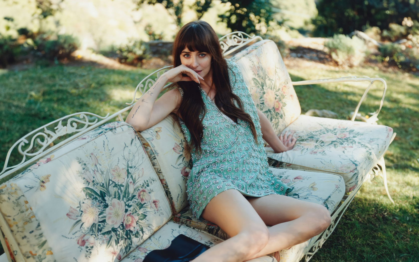 Актриса Дакота Джонсон в платье сидит на диване