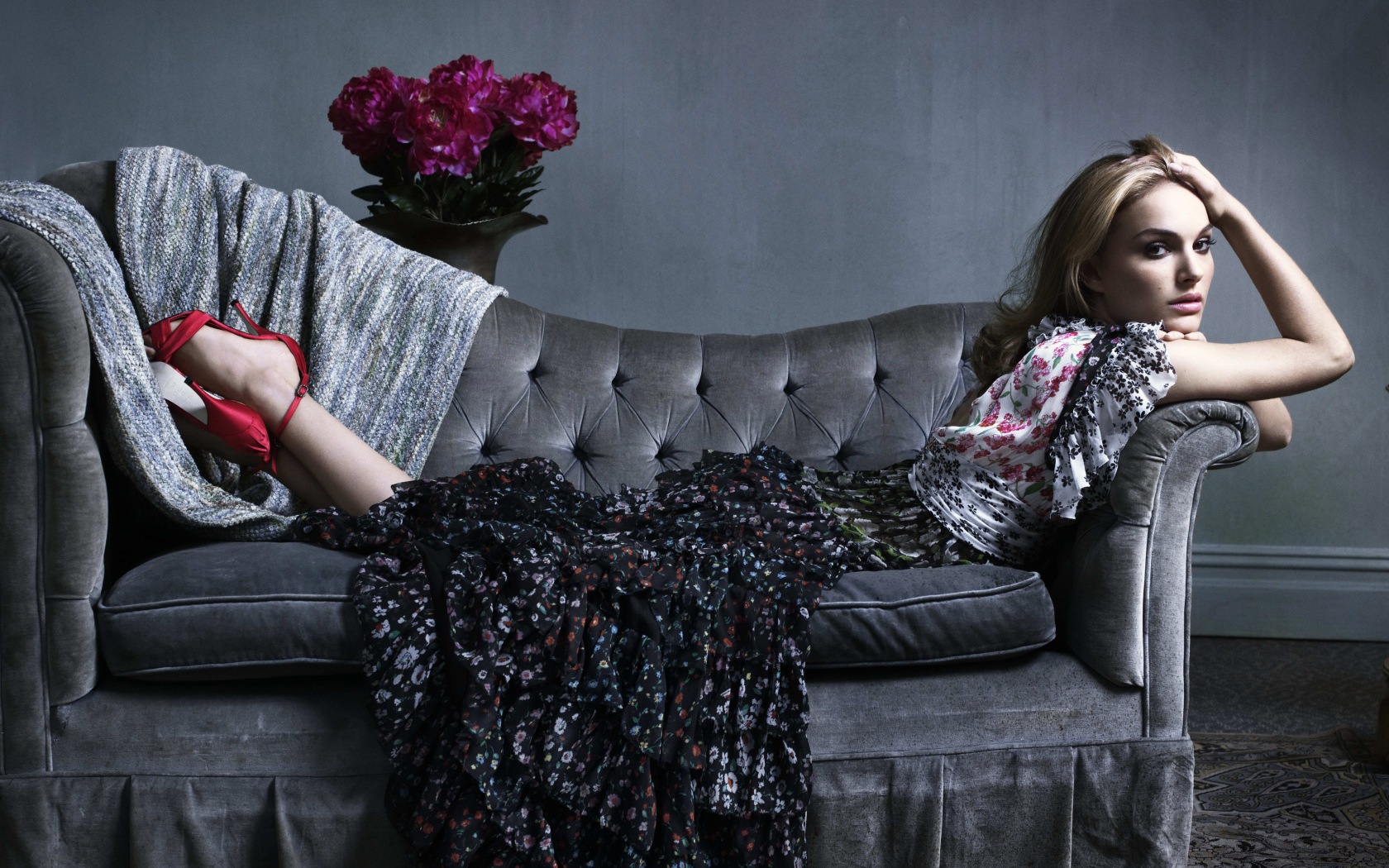 Актриса Натали Портман в платье лежит на сером диване