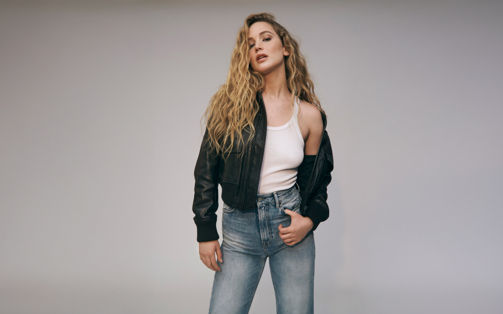 Американская актриса Дженнифер Лоуренс  в джинсах на сером фоне