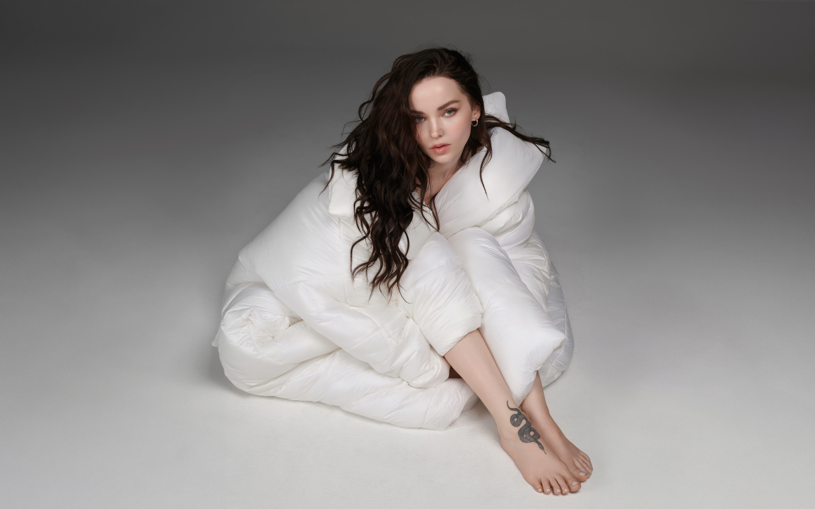 Красивая брюнетка Дав Кэмерон в белом костюме на сером фоне