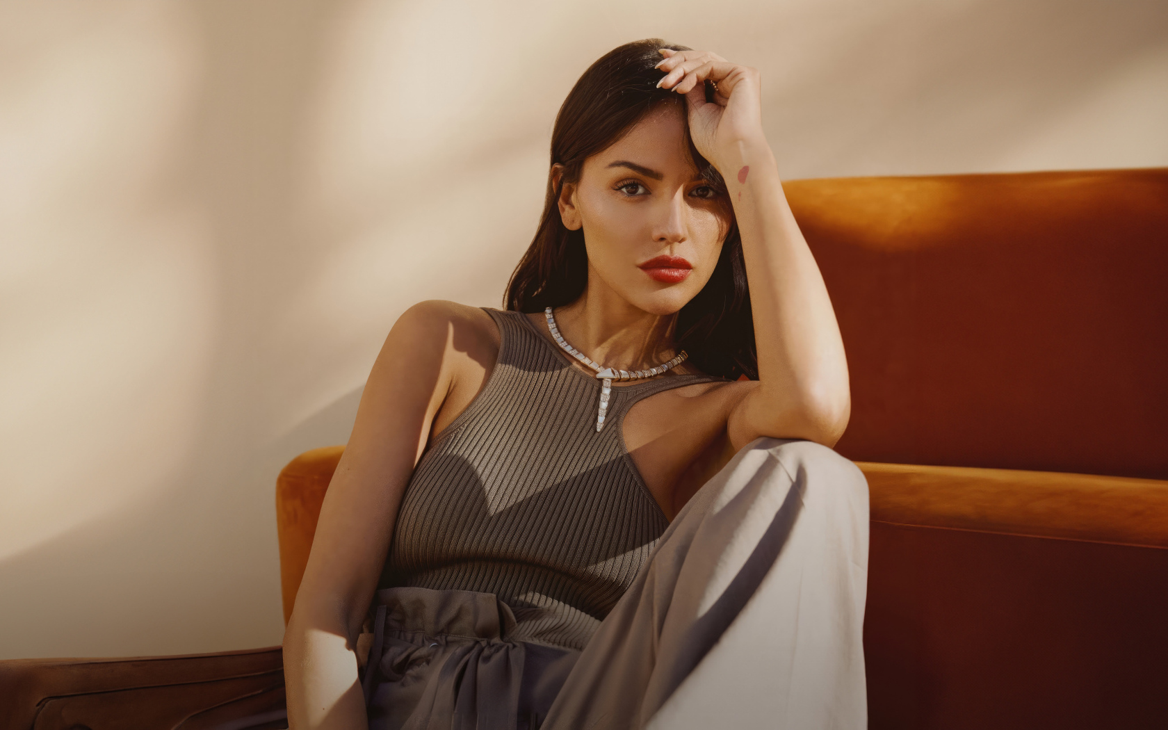 Красивая брюнетка, актриса Эйса Гонсалес сидит у дивана