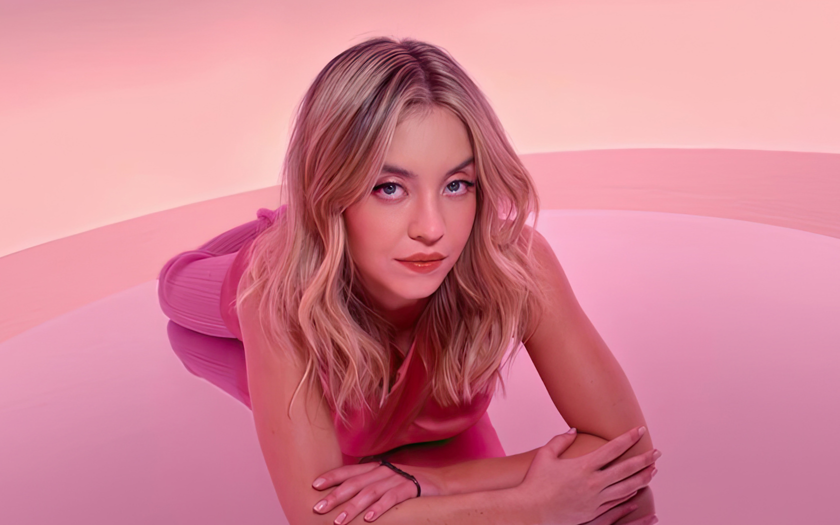 Милая блондинка Сидни Суини лежит на розовом фоне