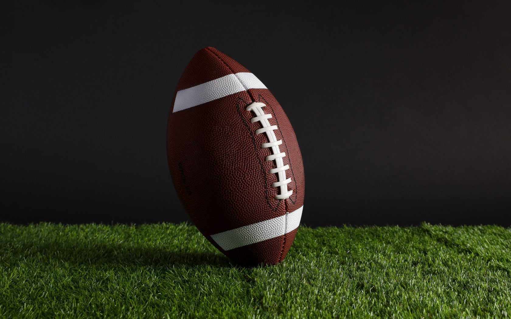 Новый кожаный мяч для американского футбола на траве