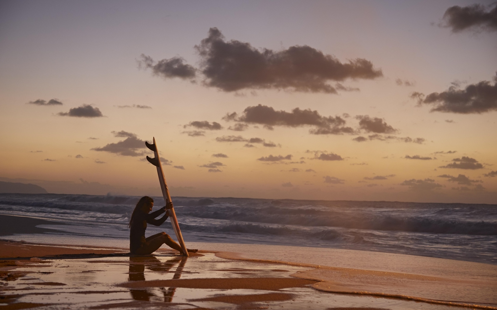 Девушка серфингистка сидит на берегу моря