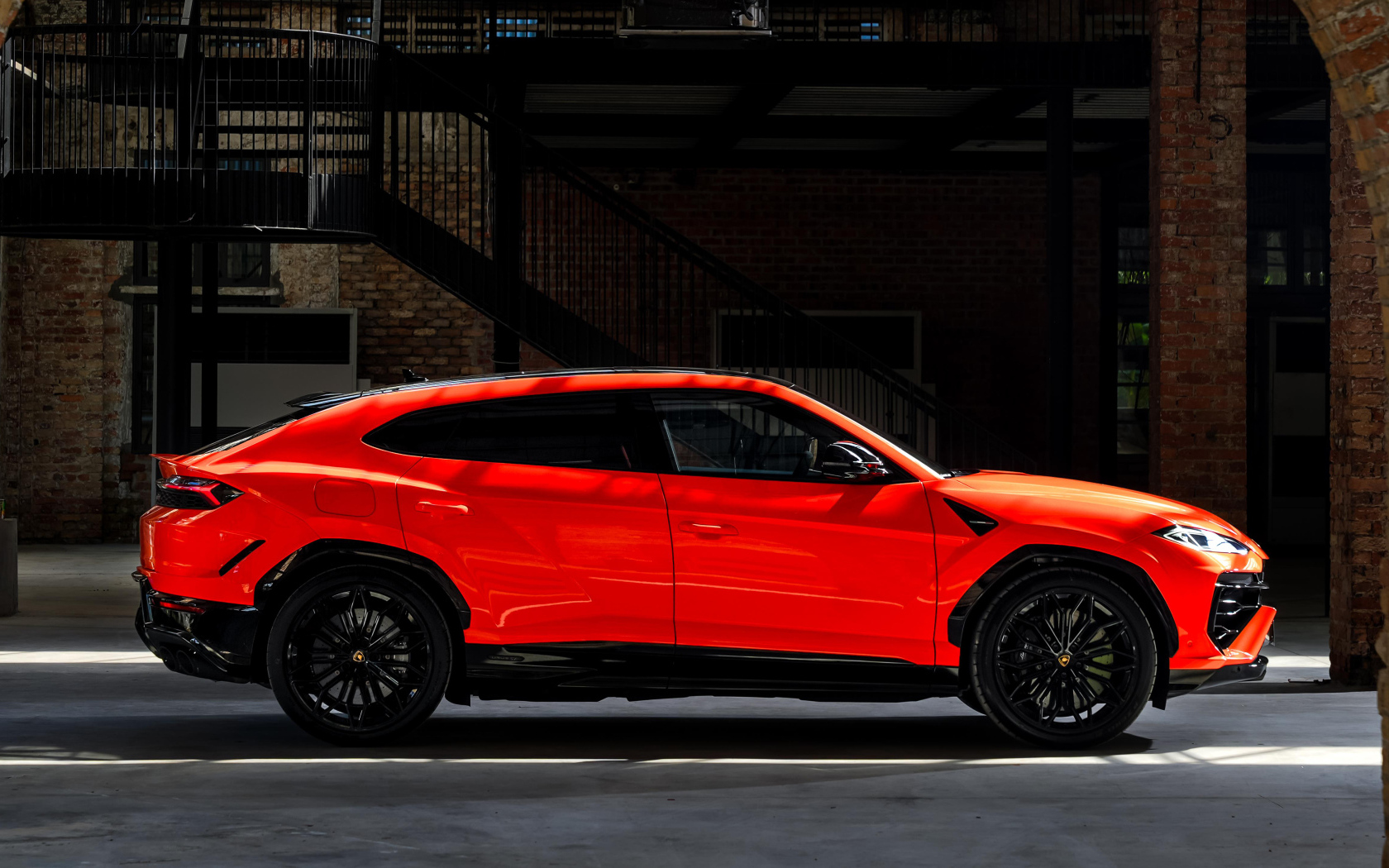 Вид сбоку на красный внедорожник Lamborghini Urus