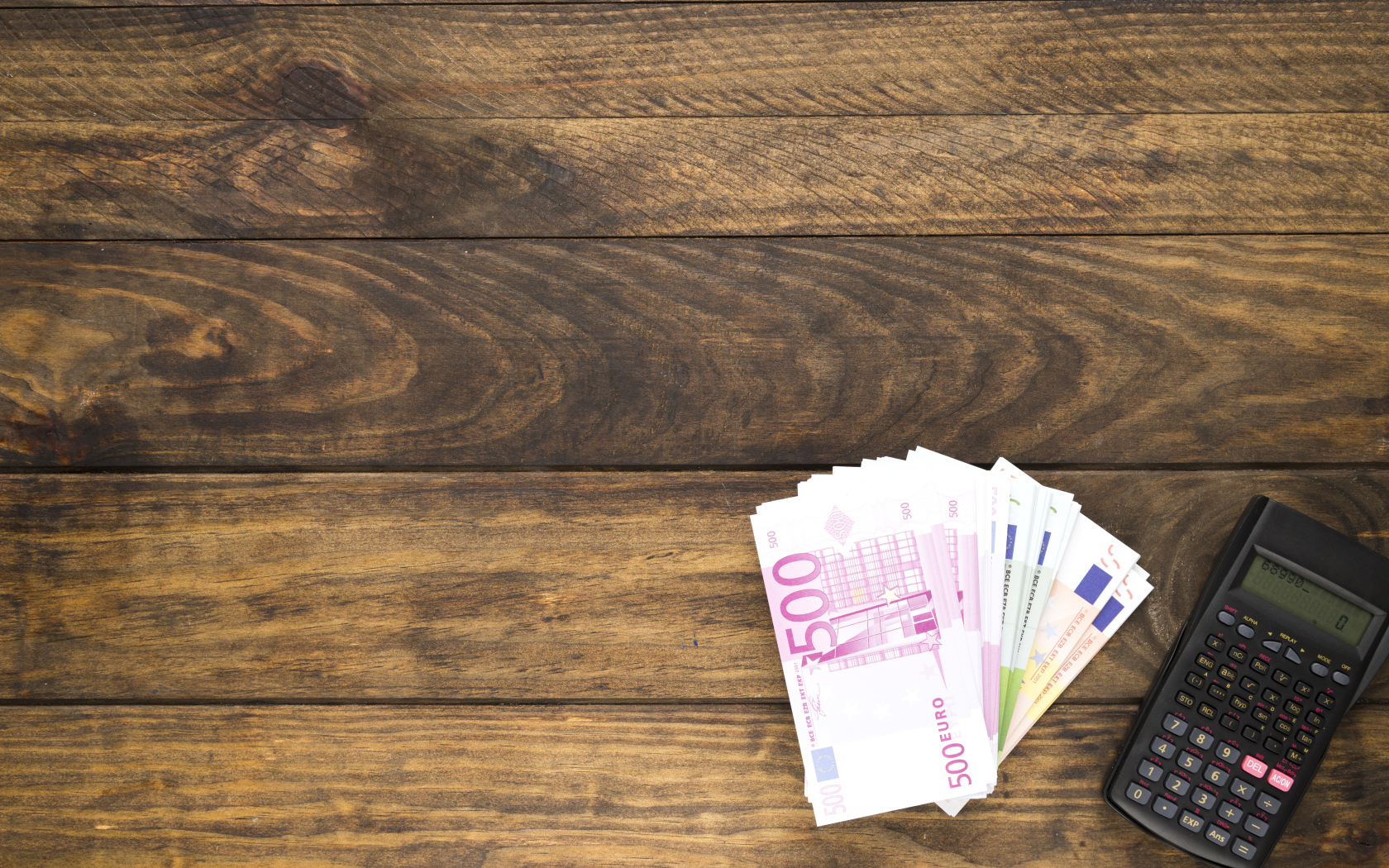 Купюры и калькулятор на деревянном фоне