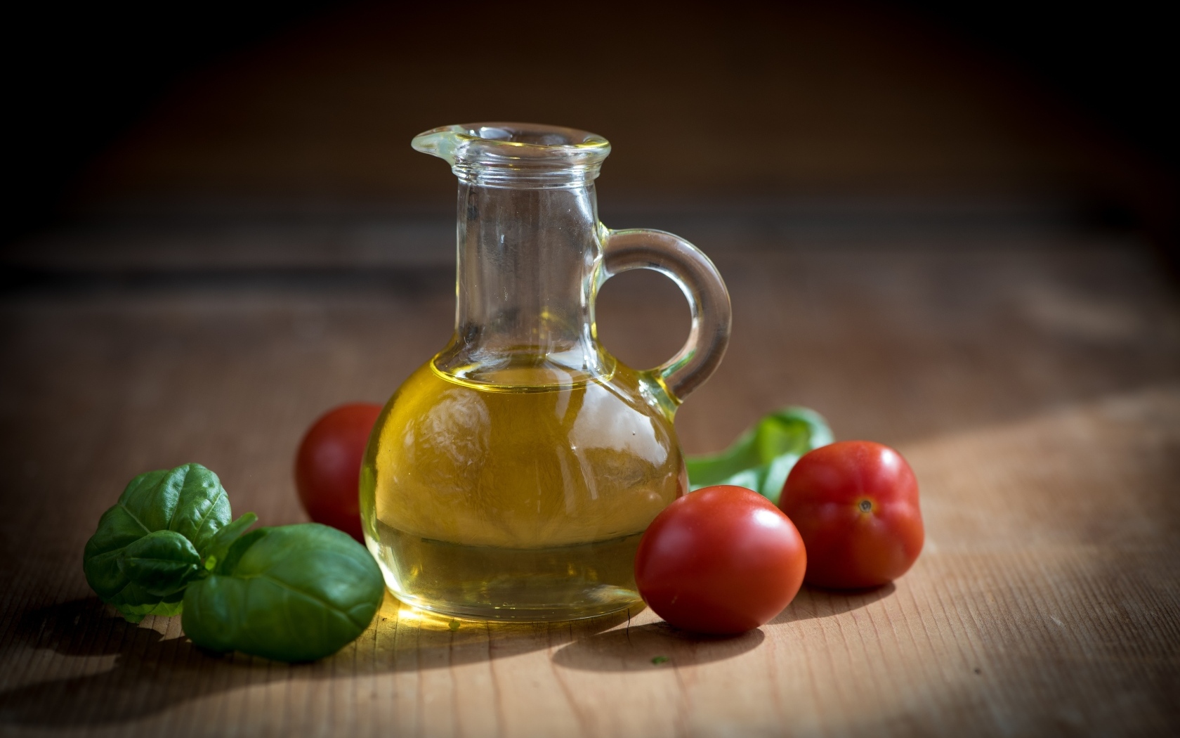 Оливковое масло на столе с базиликом и помидорами