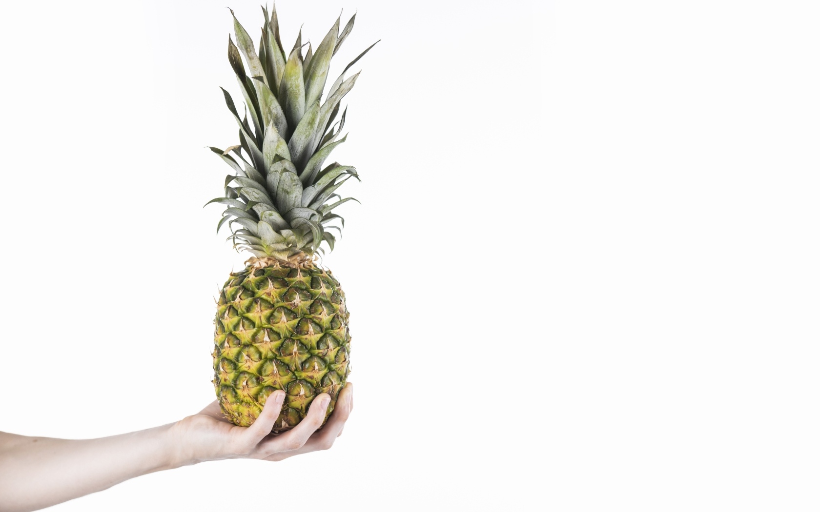 Большой ананас в руке на белом фоне