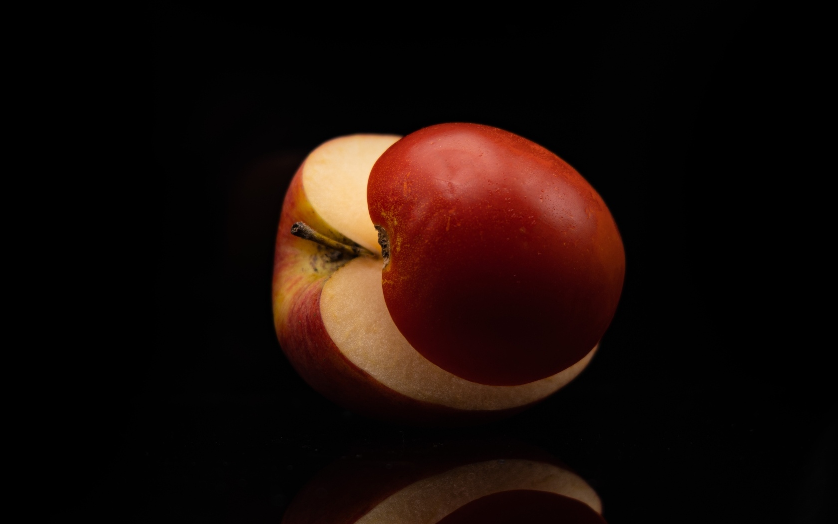 Разрезанное на половинки красное яблоко на черном фоне