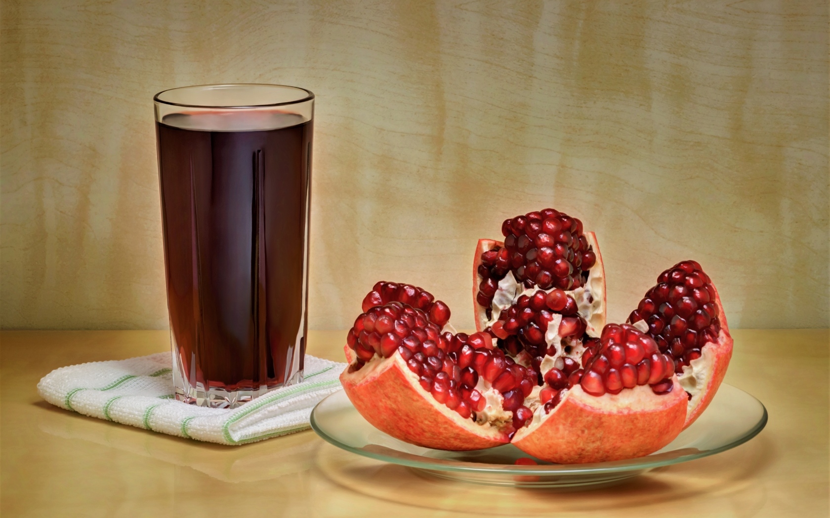 Красный гранат на столе со стаканом сока