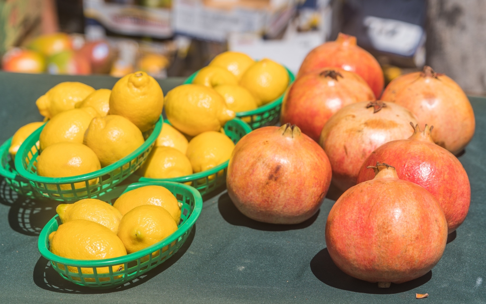 Желтые лимоны и красные плоды граната на столе