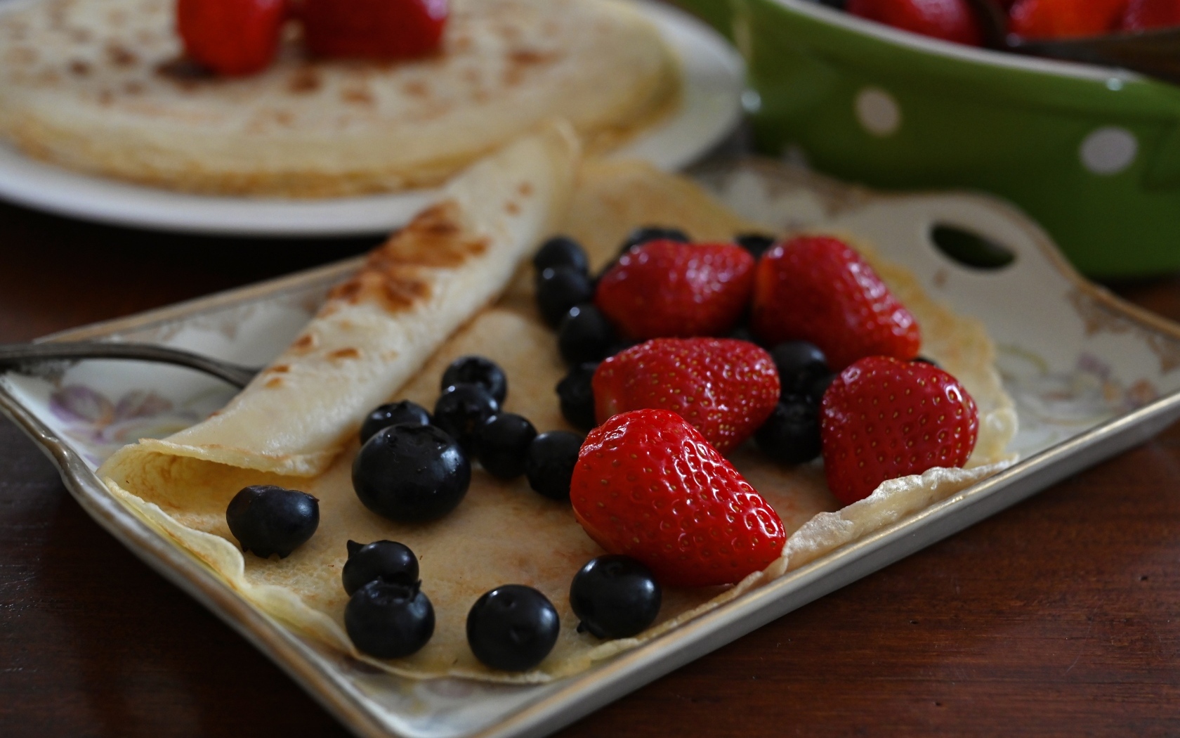 Блин с ягодами черники и клубники на тарелке