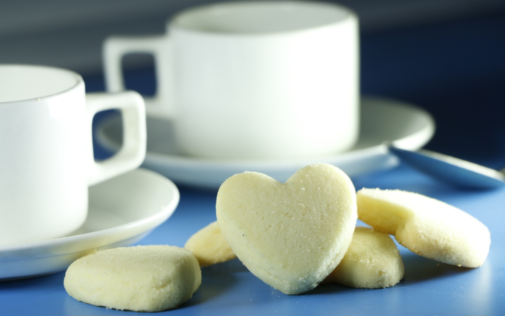 Сладкое печенье в форме сердца с кружками на столе