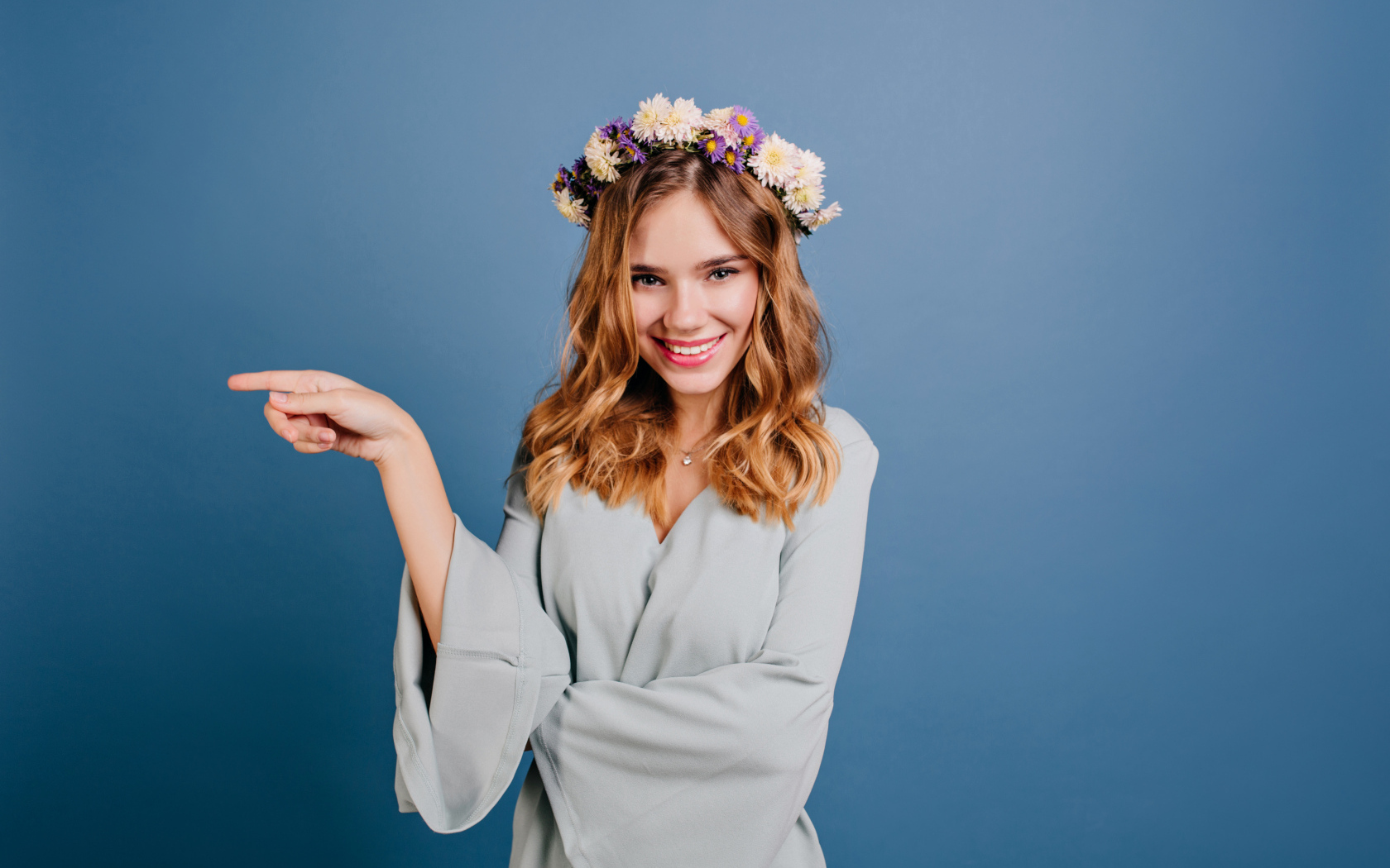 Милая улыбающаяся девушка с венком на голове на сером фоне