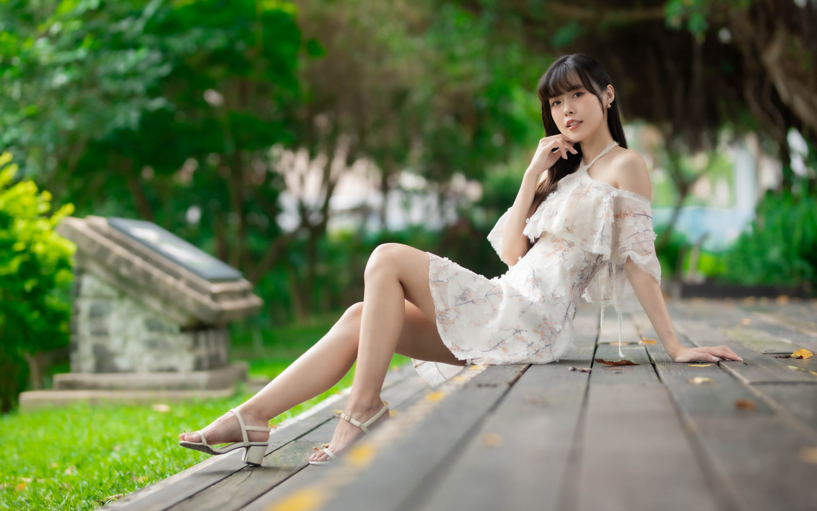 Симпатичная молодая азиатка сидит на деревянном покрытии