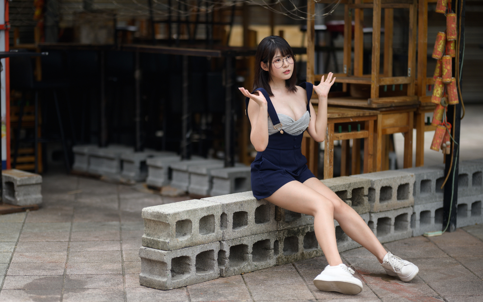 Молодая азиатка в очках сидит на шлакоблоке