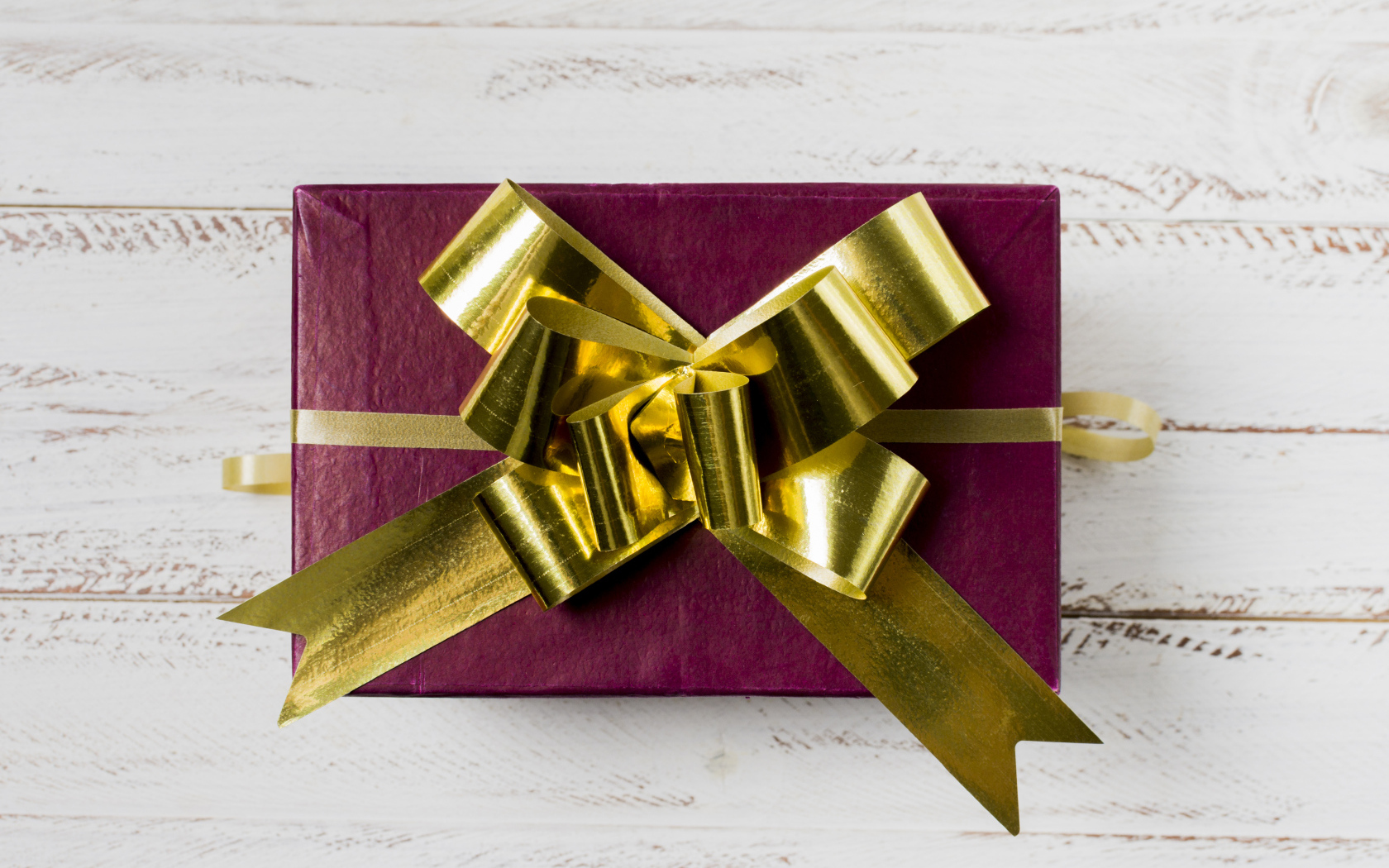 Красная коробка с подарком с золотым бантом на столе