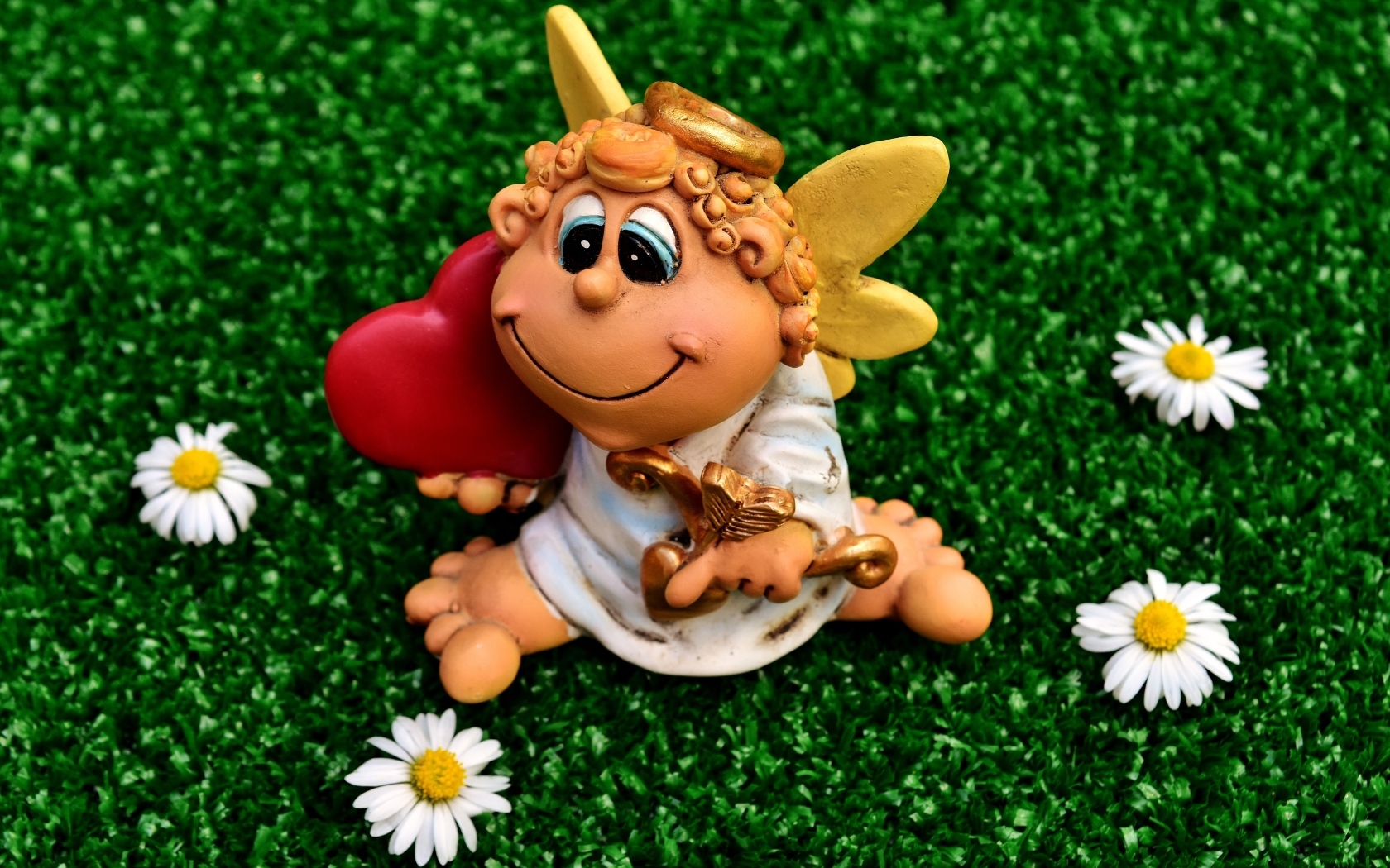 Статуэтка ангела на зеленой траве с белыми ромашками