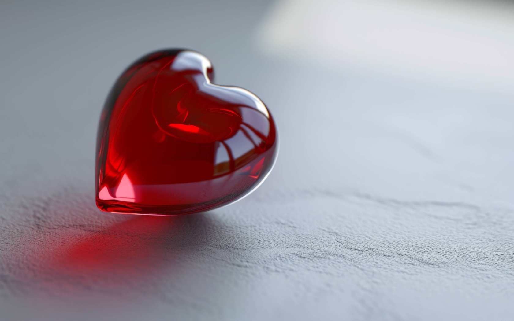 Красное стеклянное сердце на сером столе