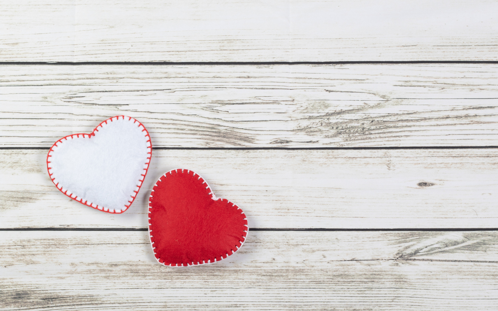 Белое и красное сшитое сердце на деревянном фоне