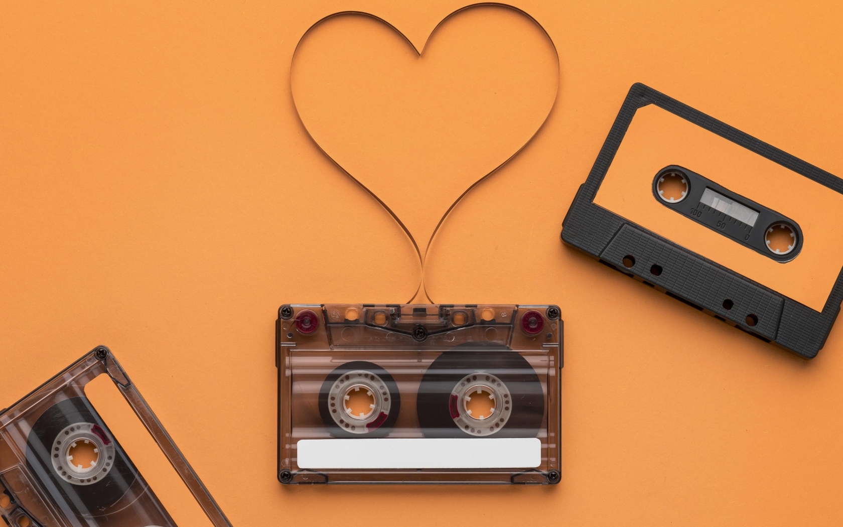 Кассеты и сердце из ленты на оранжевом фоне