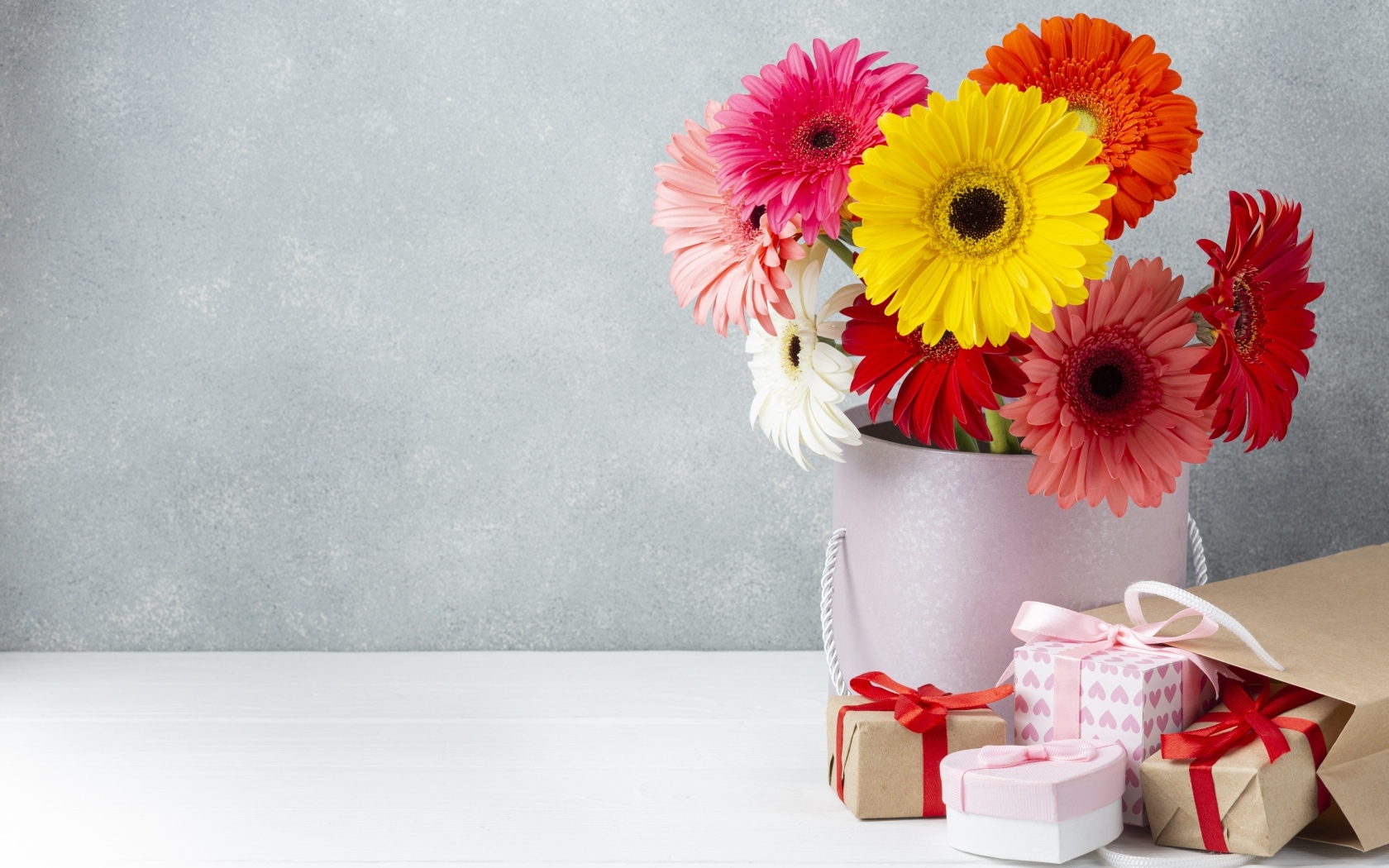 Букет разноцветных цветов герберы на столе с подарками