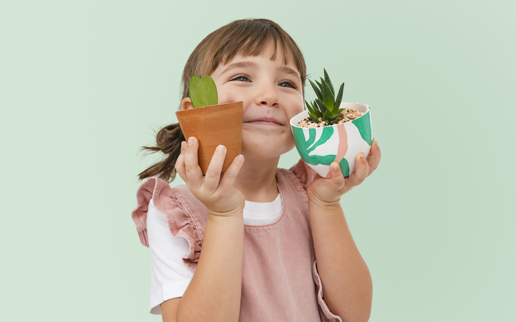 Маленькая девочка с комнатными цветами в руках